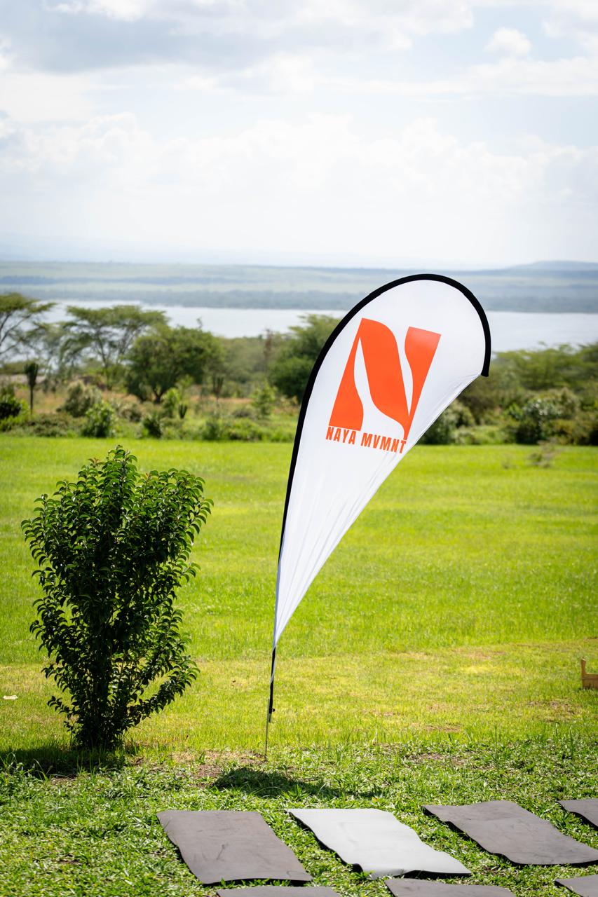 White NAYA MVMNT flag overlooking a green outdoor event space